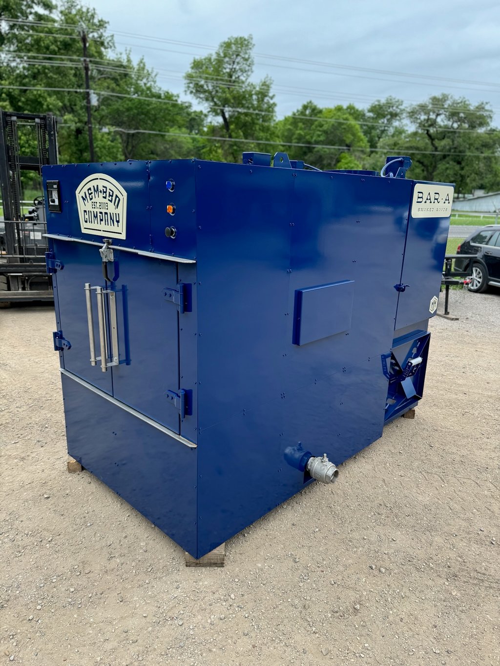 Blue M&M rotisserie smoker with the M&M BBQ Company badge