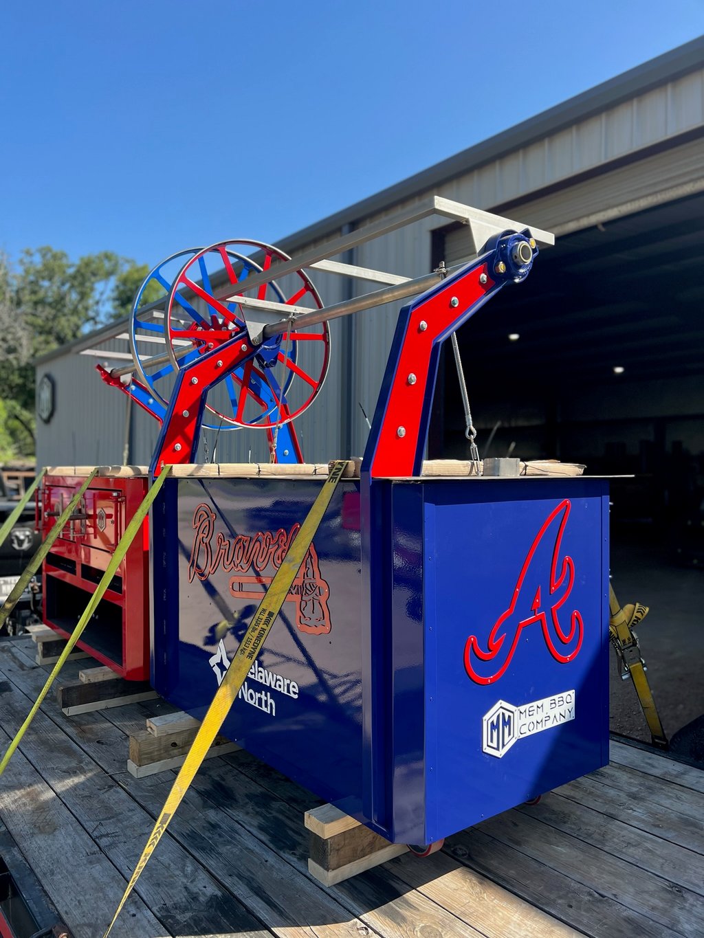 Blue El Rey woodfire grill with Atlanta Braves branding, strapped to a trailer