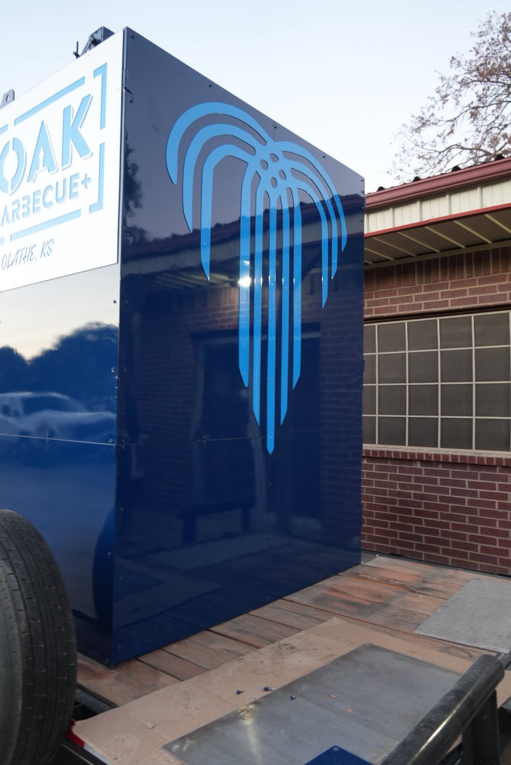 Navy rotisserie smoker with a light blue fountain logo on a trailer
